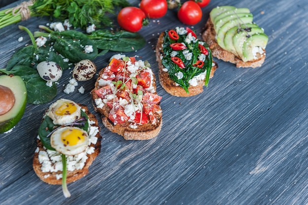 Smaczna i pyszna bruschetta z pomidorami, szpinakiem, czerwoną papryczką chili z awokado i serem pleśniowym.