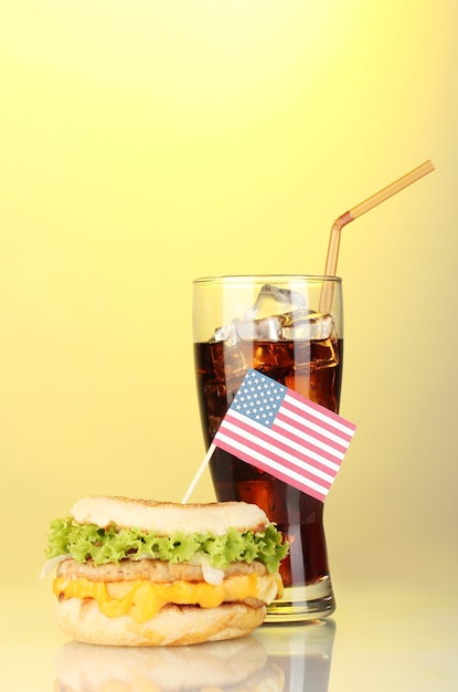 Smaczna kanapka z amerykańską flagą i colą na żółtym tle