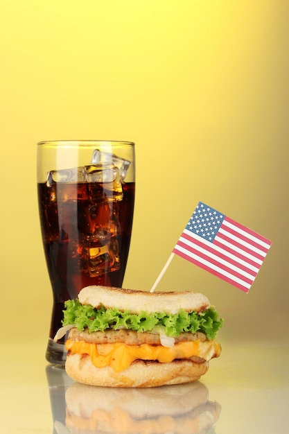 Zdjęcie smaczna kanapka z amerykańską flagą i colą na żółtym tle