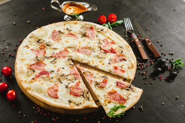 Smaczna pizza mięsna z różnymi składnikami na czarnym tle