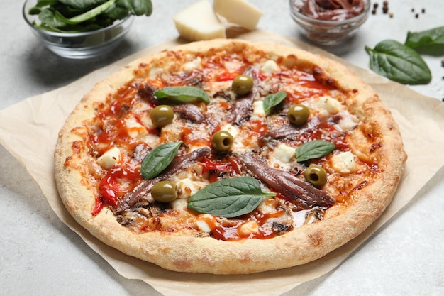 Smaczna pizza z anchois i składnikami na białym stole