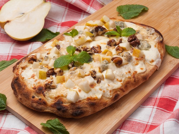 Smaczna rzymska pizza z gruszką i gorgonzolą ozdobiona listkami mięty