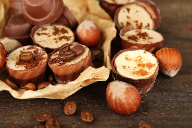 Smaczne cukierki czekoladowe z ziarnami kawy i orzechami na drewnianym tle