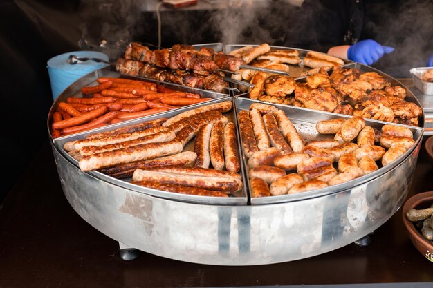 Smaczne gorące kiełbaski z grilla skrzydełka z kurczaka i grill na rynku ulicznym gotowe do spożycia