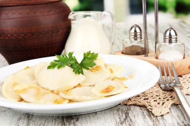 Smaczne kluski ze smażoną cebulą na białym talerzu na jasnym tle