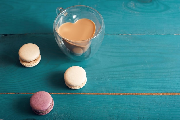 Smaczne macarons migdałowe i kawa z mlekiem na niebieskiej powierzchni drewna Romantyczny styl vintage