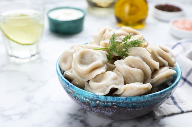 Smaczne pierogi w misce podawane na białym marmurowym stole