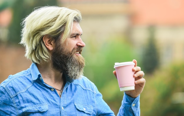 Smaczne śniadanie brodaty mężczyzna pije kawę podczas chodzenia na zewnątrz brodaty hipster facet ubrany na co dzień lubi relaks w weekendowy poranek napoje koncepcja student na przerwę na kawę