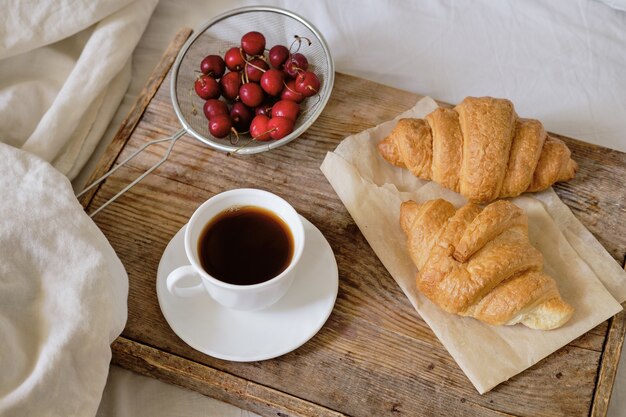 Smaczne śniadanie Ze świeżym Croissantem, Kawą, Wiśniami Na Drewnianej Tacy. Espresso Na Tacy śniadaniowej