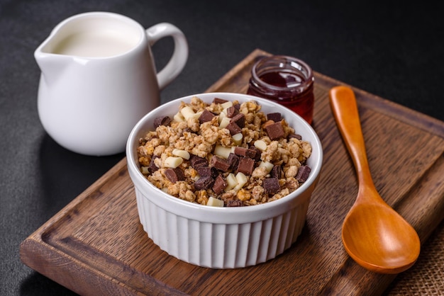 Smaczne zdrowe śniadanie z płatkami zbożowymi granola czekoladowe mleko i dżemem na ciemnym betonowym tle