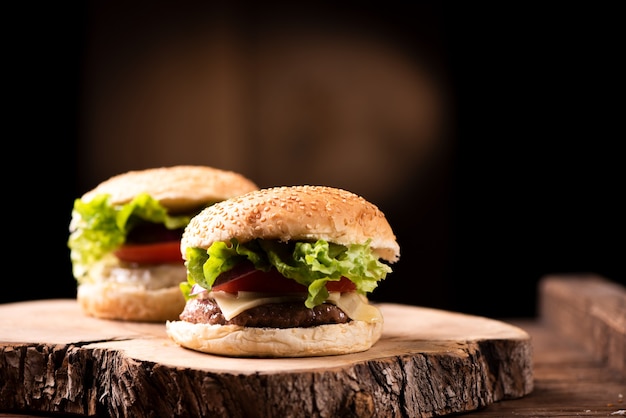 Smaczny grillowany burger wołowy z sałatą, serem i cebulą podany na desce do krojenia z copyspace