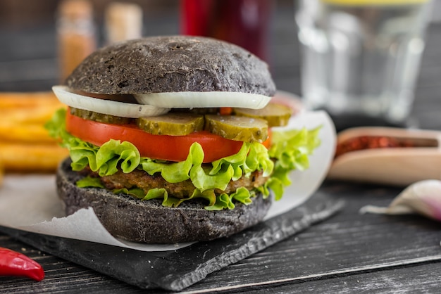 Smaczny hamburger z mięsem i warzywami na ciemnym tle. Fast food. Może być używany jako tło