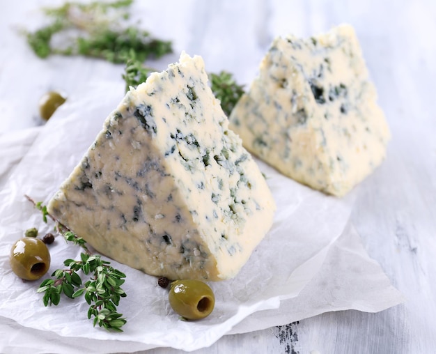 Smaczny niebieski ser z tymiankiem i oliwkami na drewnianym stole