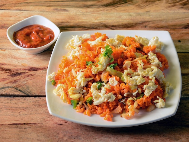 Smaczny Schezwan Smażony ryż z jajkiem i sosem pomidorowym podany w białym talerzu na rustykalnym drewnianym tle Kuchnia indyjska selektywna ostrość