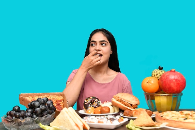 smakosz dziewczyna siedząca przy stole z owocami jedząca babeczkę patrząc na lewo indyjski model pakistański