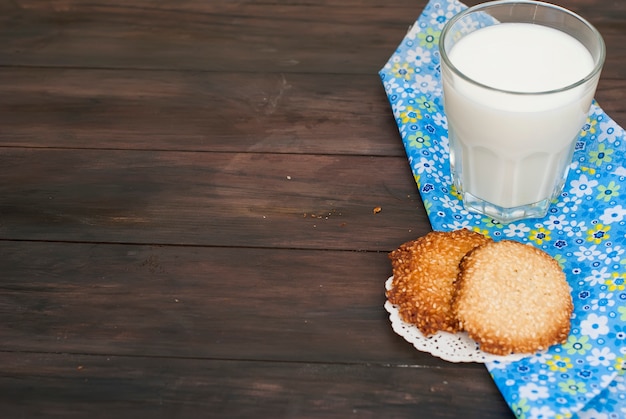 Smakowici ciastka i szkło mleko na nieociosanym drewnianym tle