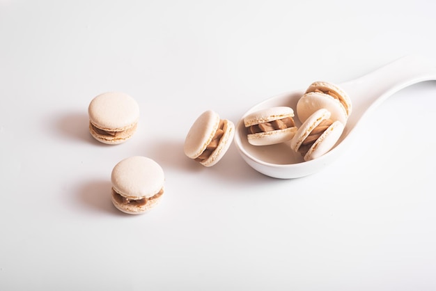 Smakowici migdałowi macarons w ceramicznej białej łyżce na białym tle Odbitkowa przestrzeń