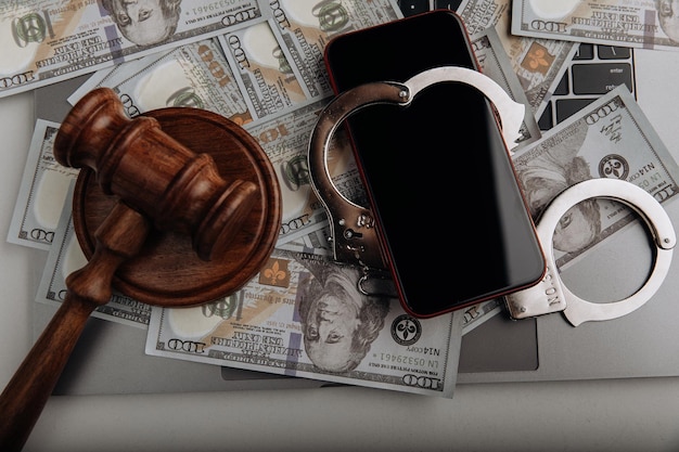 Smartfon z kajdankami na banknotach dolara i młotkiem sędziego Cyberprzestępczość i koncepcja prawa