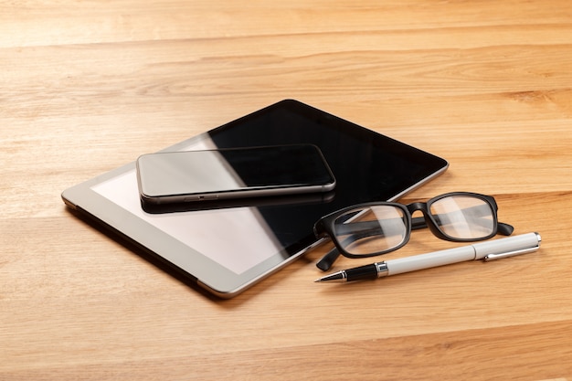 Smartphone i cyfrowa pastylka na drewnianym biurku