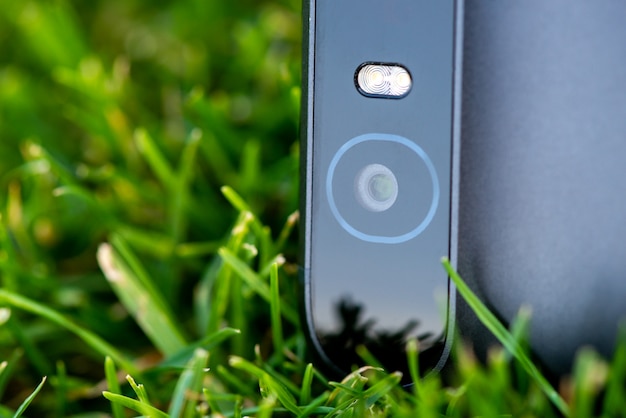 Smartphone kamera z błyskową zakończenie fotografią na zielonej trawie