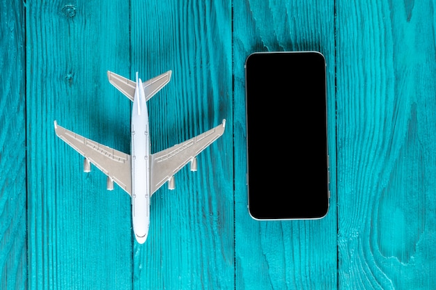 Smartphone, z czarnym ekranem, model samolotu na niebieskim drewnianym