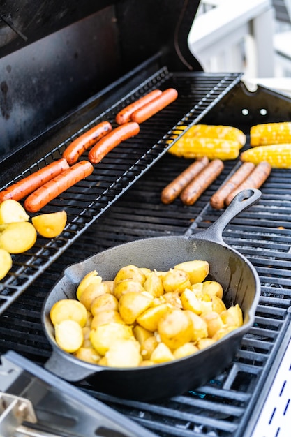 Smażenie małych złocistych ziemniaków na żeliwnej patelni na grillu gazowym na świeżym powietrzu.