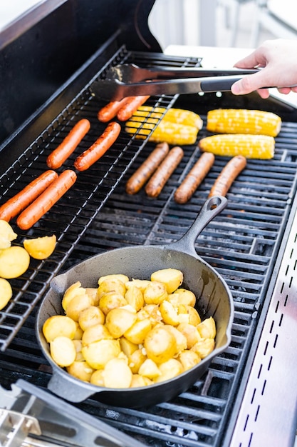 Smażenie małych złocistych ziemniaków na żeliwnej patelni na grillu gazowym na świeżym powietrzu.