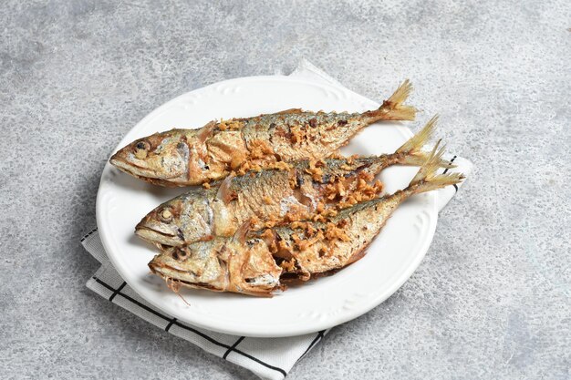 smażona ryba posypana smażonym czosnkiem na białym talerzu