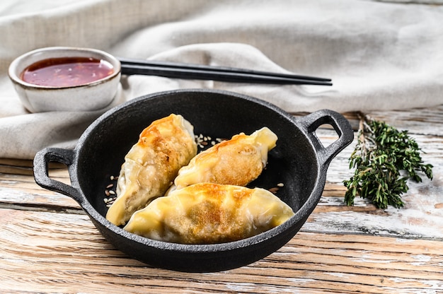 Smażone Japońskie Pierogi Gyoza Na Patelni. Białe Tło Drewniane. Widok Z Góry.