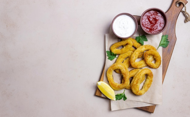 Smażone krążki kalmarów z dwoma sosami, cytryną i ziołami. Fast food. Przystawka.