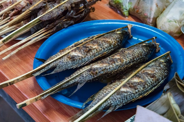 Smażone ryby w soli na grillu na ladzie handlarza. Tradycyjne azjatyckie jedzenie uliczne. Szaszłyki z Pieczonej Ryby - Styl Laosu.