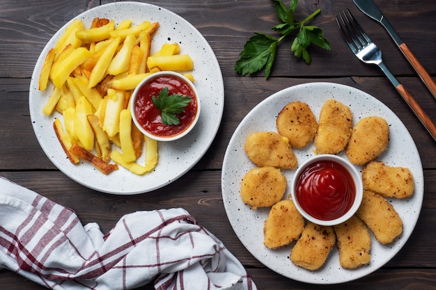 Smażone ziemniaki i nuggetsy z kurczaka z pomidorowym sosem keczupowym. Fast food koncepcja niezdrowej żywności.