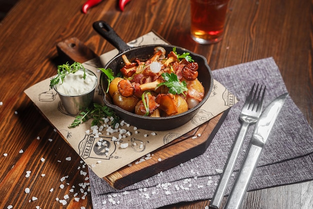Zdjęcie smażone ziemniaki z grzybami i kurczakiem w żeliwnej patelni ciemna i nastrojowa nowa