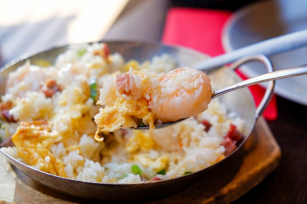 Zdjęcie smażony ryż z krewetkami jeść w gorącej patelni używanej jako talerz z drewnianym stołem.