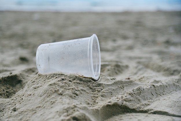 Śmieci w morzu z plastikowym kubkiem na plaży piaszczyste, brudne morze na wyspie Problem środowiskowy zanieczyszczenia śmieciami w oceanie