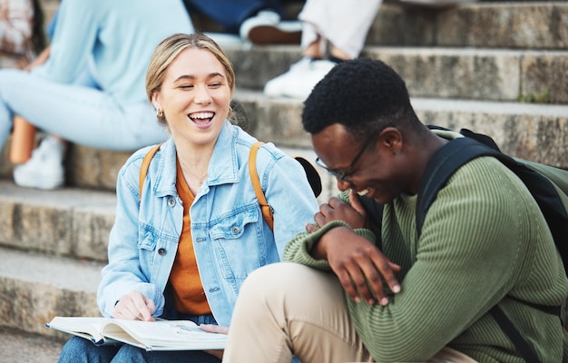 Śmiejący się studenci rezerwują lub studiują na schodach w szkole uniwersyteckiej lub kampusie uniwersyteckim do egzaminu testowego lub projektu Uśmiechnij się szczęśliwy lub łącząc przyjaciół i wsparcie celów edukacyjnych lub pomoc w badaniach