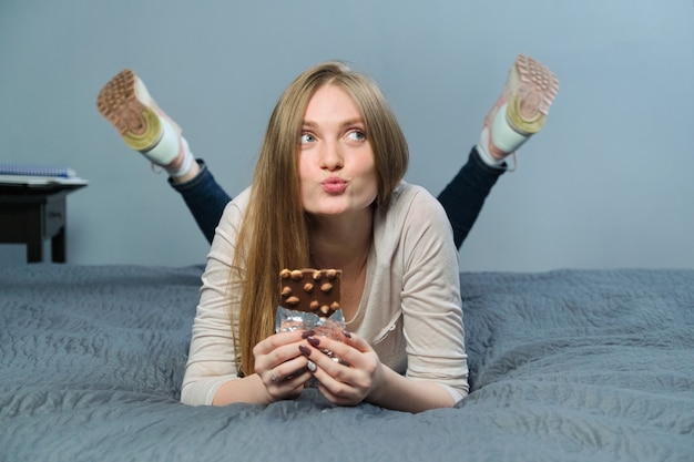 Śmieszna emocjonalna dziewczyna trzyma dojną czekoladę z całymi dokrętkami w jej ręce