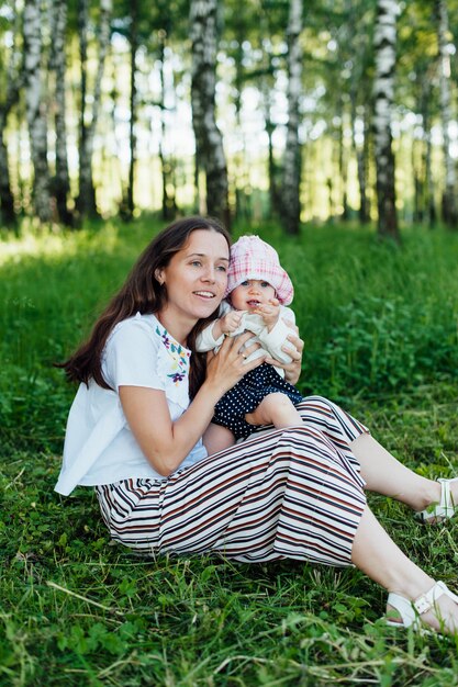 Śmieszna mama z dziecka obsiadaniem na trawie