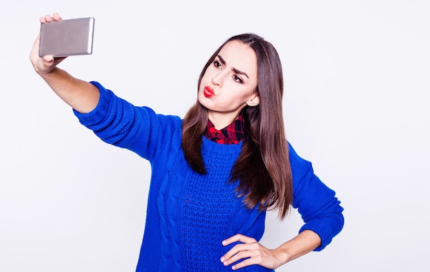 Śmieszna młoda brunetka robi selfie zdjęcie na swoim smartfonie