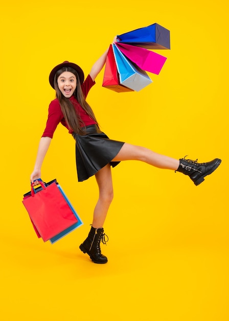 Śmieszna nastolatka trzyma torbę na zakupy cieszącą się sprzedażą odizolowaną na żółto Portret nastolatka uczennica