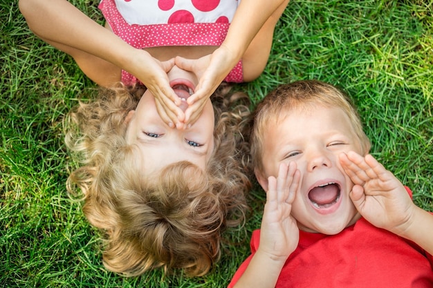 Zdjęcie Śmieszne dzieci krzyczą na zewnątrz szczęśliwe dzieci leżące na zielonej trawie koncepcja komunikacji