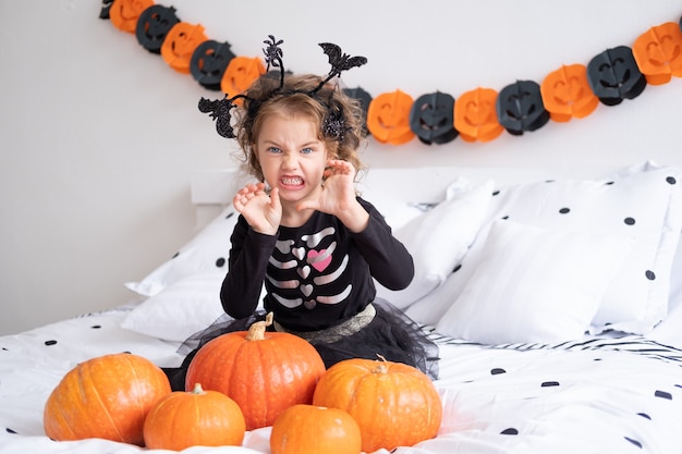 Śmieszne dziecko kaukaski dziewczyna w stroju czarownicy zabawy w urządzone na halloween sypialni.