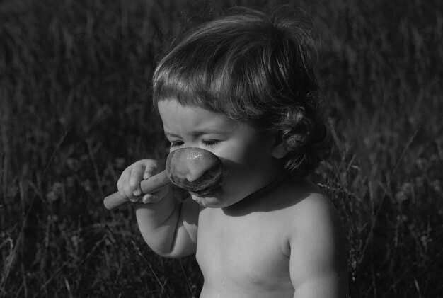 Śmieszne dziecko w parku zjada się z dużą drewnianą łyżką niewyraźne tło natury zdrowe odżywianie dla k