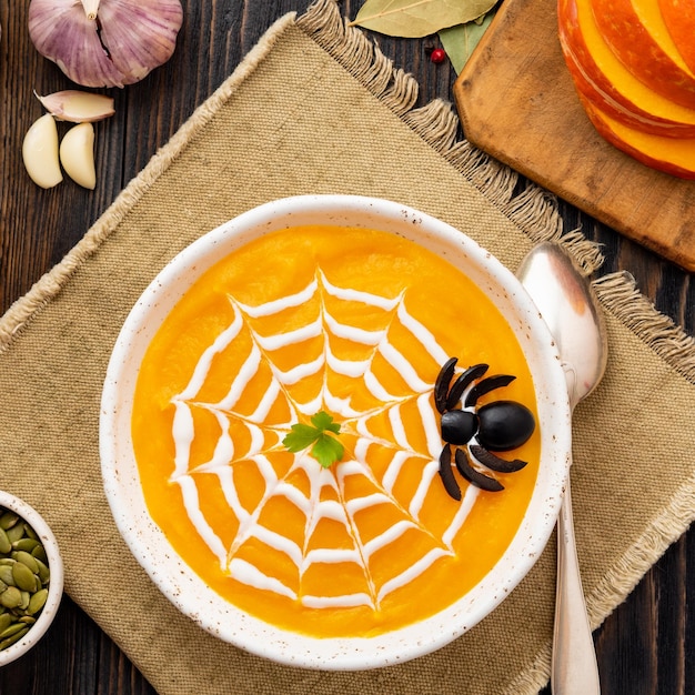 Zdjęcie Śmieszne jedzenie na halloween puree z dyni zupa pajęcza sieć ciemny stary drewniany blat widok