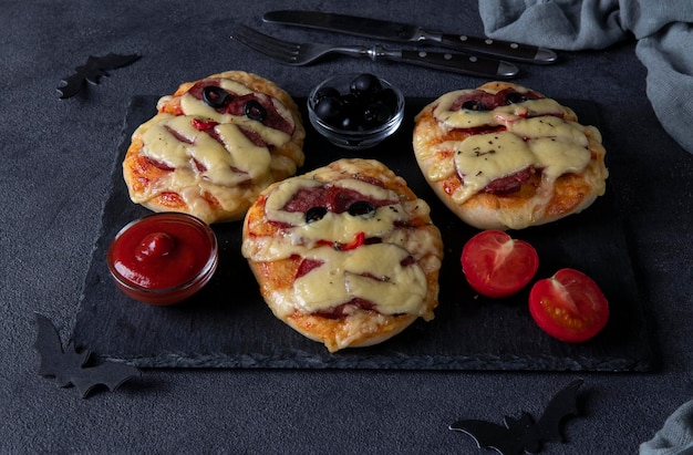 Śmieszne Mini Pizze Mumie Z Kiełbasą I Serem Na Halloween Podawane Z Czarnymi Oliwkami