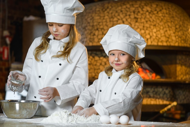 Zdjęcie Śmieszne szczęśliwy dziewczyna szefa kuchni gotowanie w kuchni restauracji