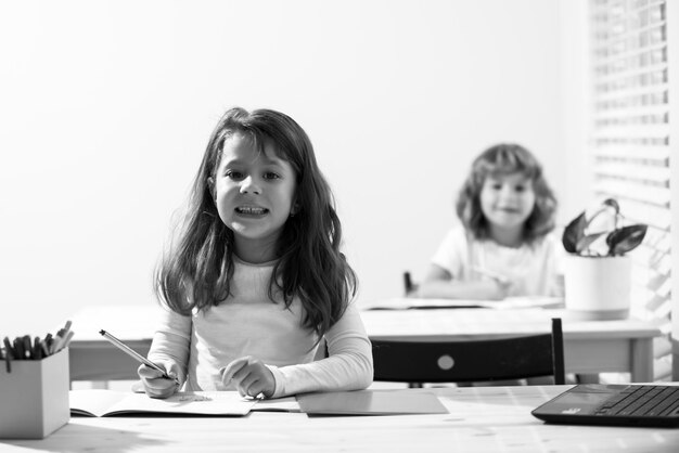 Śmieszne uśmiechnięte dzieci w klasie w szkole Uczeń i uczennica siedzą przy biurku i piszą tekst