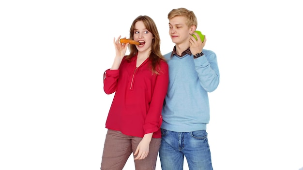 Zdjęcie Śmieszni nastolatkowie pozuje przy kamerą z owocami i warzywami odizolowywającymi na białym tle