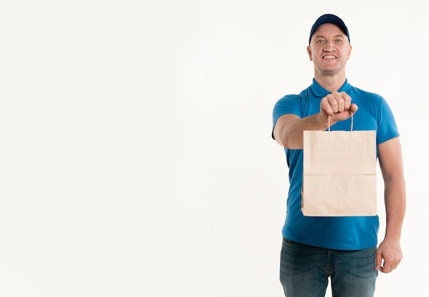 Zdjęcie smiley doręczeniowy mężczyzna trzyma papierową torbę z kopii przestrzenią
