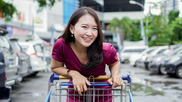 Smilling azjatycka kobieta na zakupy z wózkiem